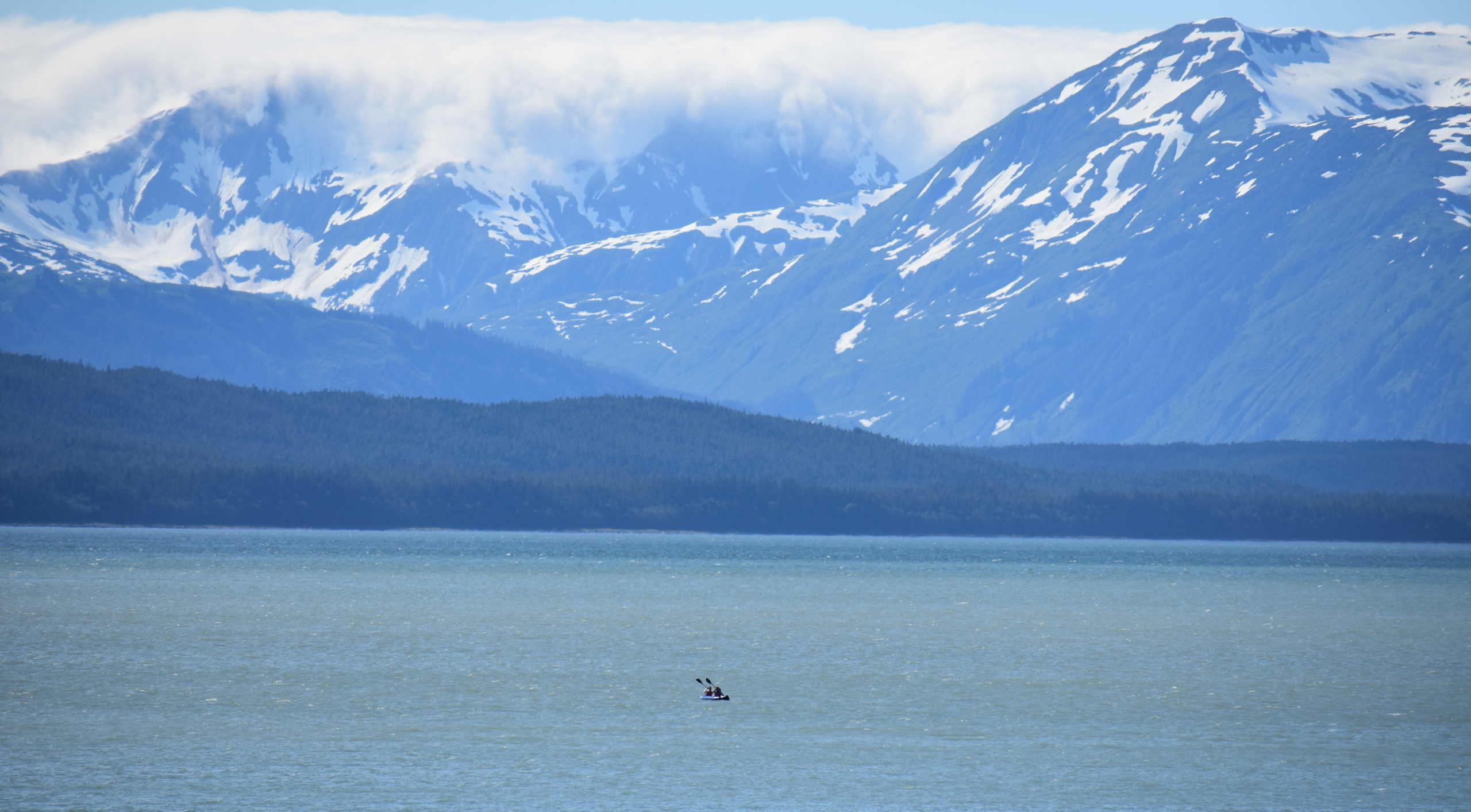 A kayak out in the distance with mountains in the background