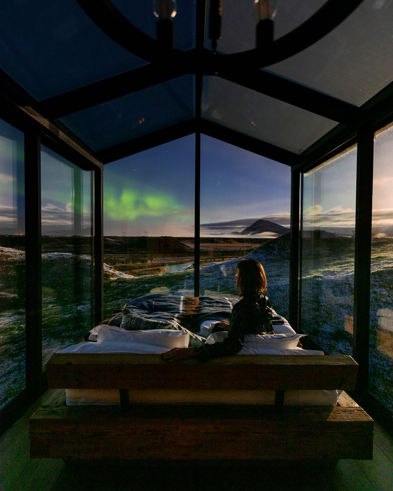 Looking at the northern lights from the bed of the Odin Panorama Glass Lodge in Iceland.